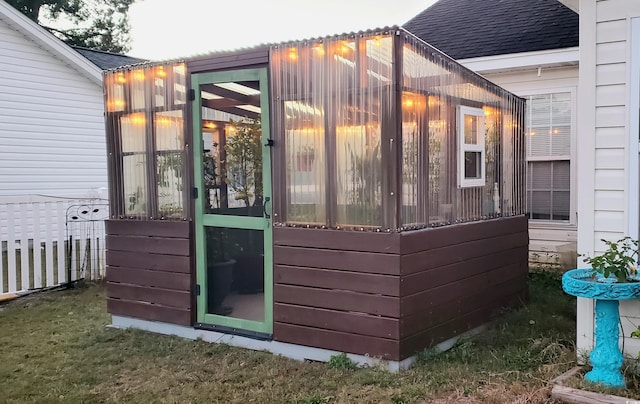 view of outbuilding featuring a sunroom and fence