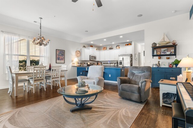 living room featuring dark wood-type flooring and ceiling fan with notable chandelier