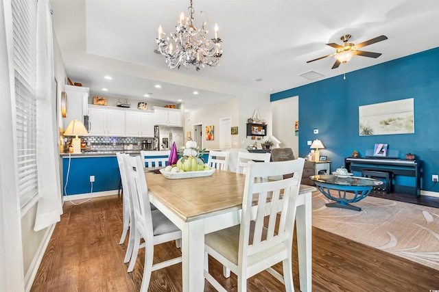 dining room with ceiling fan with notable chandelier and dark hardwood / wood-style floors