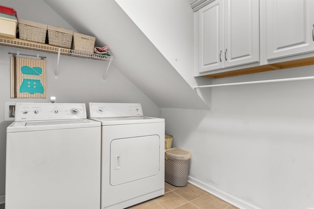 laundry room featuring washing machine and dryer, cabinets, and light tile patterned flooring