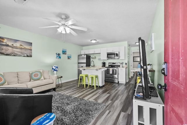 living room featuring ceiling fan, sink, dark hardwood / wood-style floors, and a textured ceiling