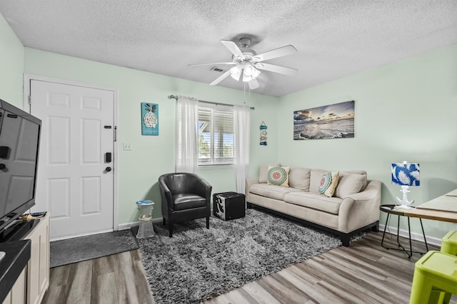 living room featuring a textured ceiling, hardwood / wood-style floors, and ceiling fan