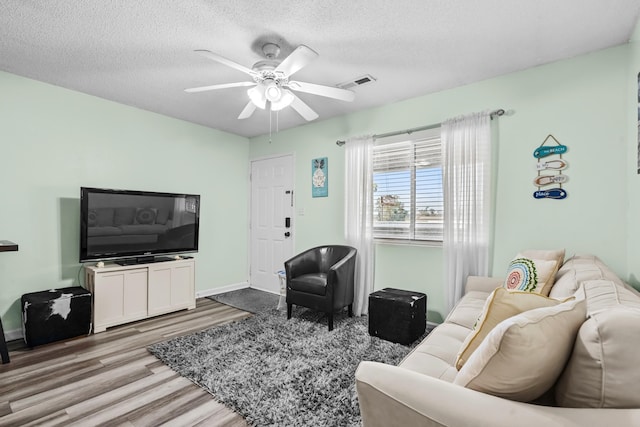 living room featuring ceiling fan, a textured ceiling, and light hardwood / wood-style flooring