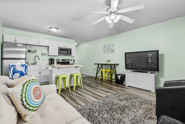 living room featuring ceiling fan, a textured ceiling, sink, and dark hardwood / wood-style flooring