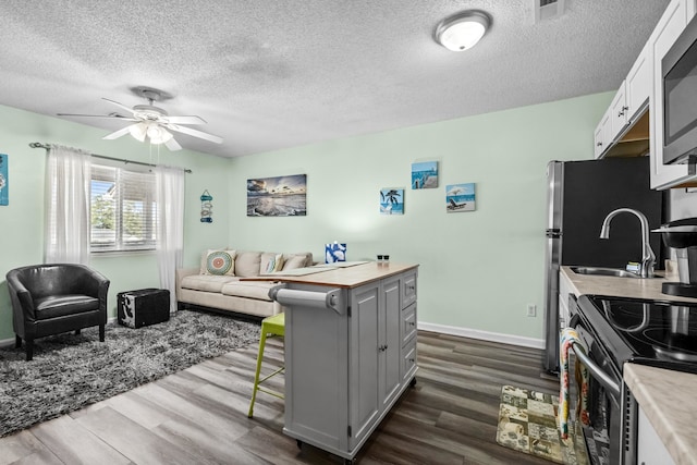 kitchen featuring appliances with stainless steel finishes, a textured ceiling, white cabinets, dark wood-type flooring, and gray cabinetry