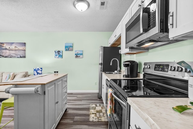 kitchen featuring a kitchen breakfast bar, white cabinetry, dark hardwood / wood-style floors, and stainless steel appliances