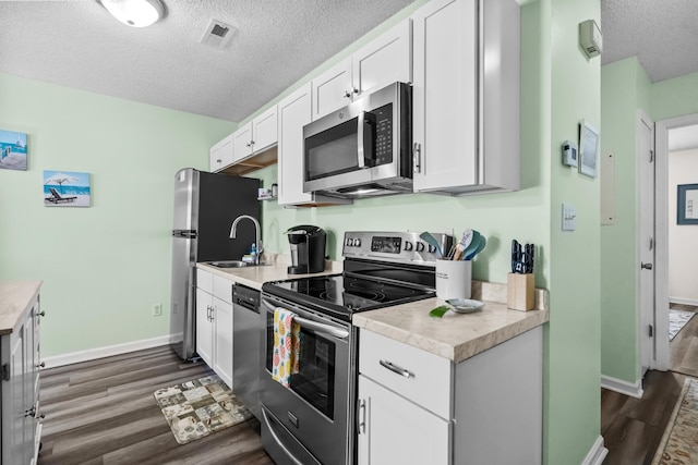 kitchen featuring sink, appliances with stainless steel finishes, dark hardwood / wood-style floors, a textured ceiling, and white cabinets