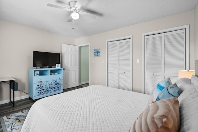 bedroom featuring dark wood-type flooring, a textured ceiling, ceiling fan, and multiple closets