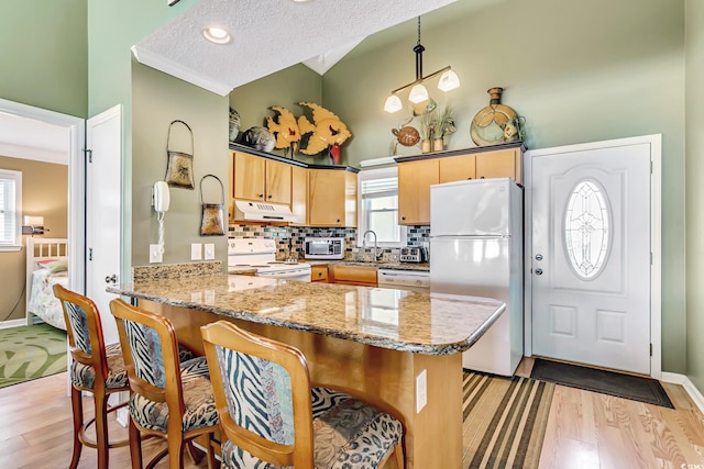 kitchen with white appliances, a textured ceiling, light wood-type flooring, and kitchen peninsula