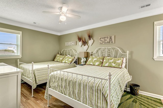 bedroom featuring hardwood / wood-style flooring, a textured ceiling, ceiling fan, and crown molding