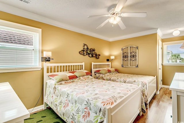 bedroom featuring hardwood / wood-style flooring, ceiling fan, a textured ceiling, and ornamental molding