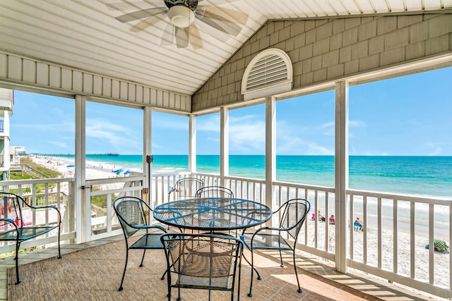 sunroom featuring a water view and a beach view