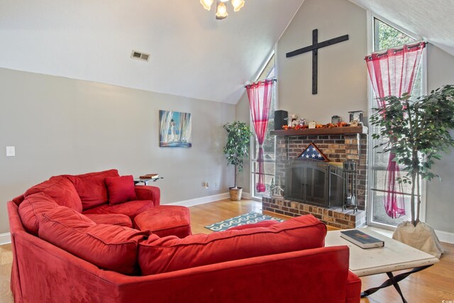 living room with a brick fireplace, lofted ceiling, and hardwood / wood-style flooring