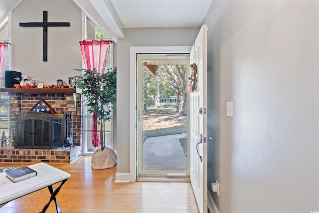 doorway to outside featuring light hardwood / wood-style floors and a brick fireplace