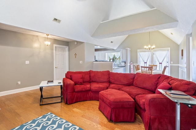 living room with lofted ceiling, a chandelier, and light hardwood / wood-style flooring