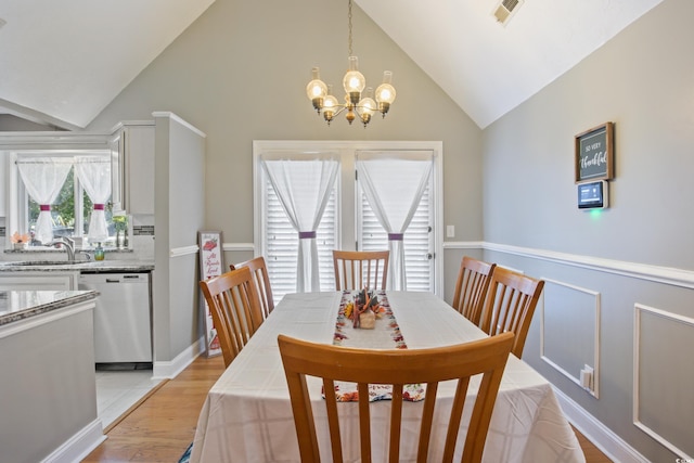 dining room with sink, vaulted ceiling, a chandelier, and light wood-type flooring