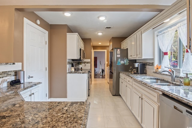 kitchen with sink, decorative backsplash, stainless steel appliances, and stone countertops