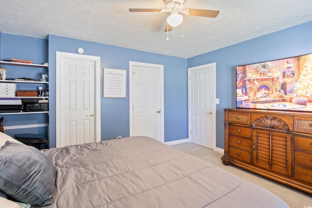 carpeted bedroom featuring multiple closets, a textured ceiling, and ceiling fan