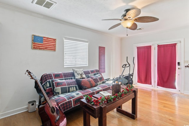 living room with ceiling fan, ornamental molding, hardwood / wood-style floors, and a textured ceiling