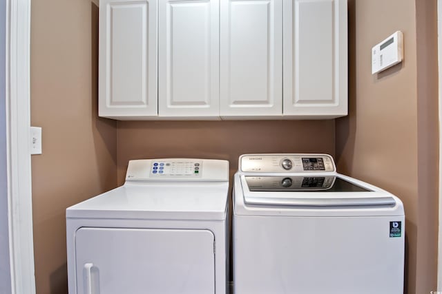 washroom with washer and clothes dryer and cabinets