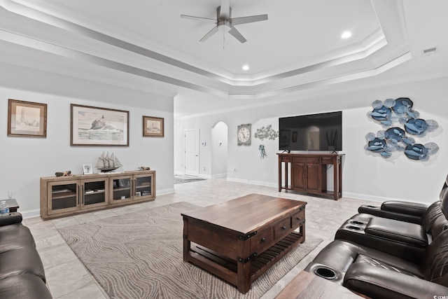 living room with visible vents, crown molding, baseboards, a tray ceiling, and arched walkways