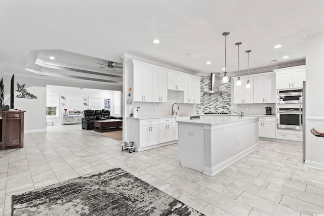 kitchen with light countertops, wall chimney range hood, stainless steel double oven, and ornamental molding