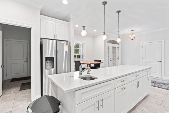 kitchen with crown molding, a center island with sink, white cabinets, stainless steel fridge, and a sink