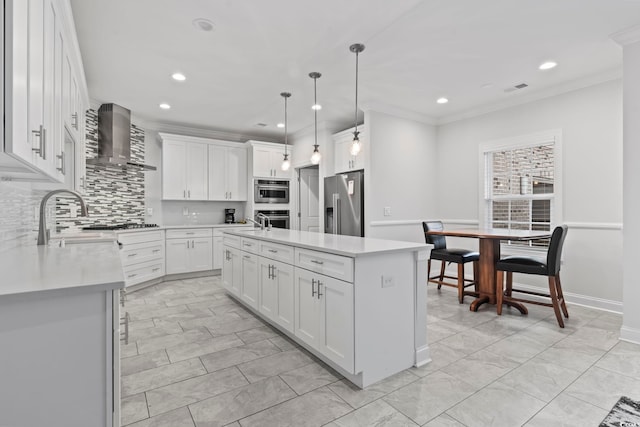 kitchen with stainless steel appliances, wall chimney exhaust hood, crown molding, and light countertops