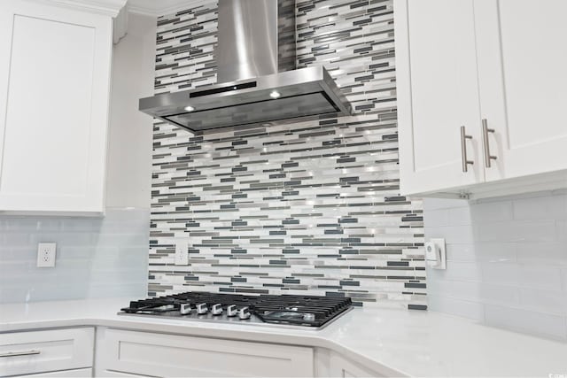 kitchen featuring light countertops, wall chimney range hood, tasteful backsplash, and stainless steel gas stovetop