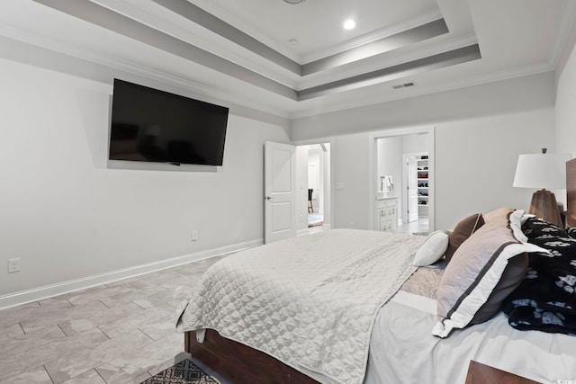 bedroom featuring baseboards, visible vents, a tray ceiling, ornamental molding, and a walk in closet