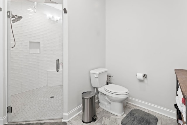 bathroom featuring toilet, baseboards, and a stall shower