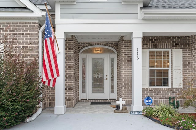 entrance to property with brick siding and roof with shingles