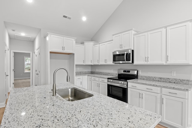 608 Britt St, Georgetown, SC 29440 - kitchen featuring stainless steel appliances, a sink, white cabinetry, lofted ceiling, and light stone countertops