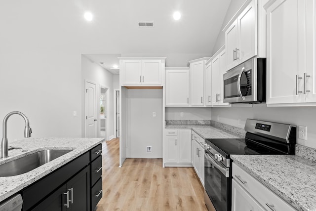 kitchen featuring visible vents, a sink, white cabinets, appliances with stainless steel finishes, and dark cabinets