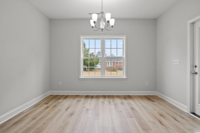 empty room featuring baseboards, a notable chandelier, and light wood-type flooring