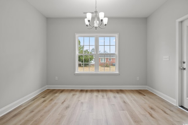 unfurnished room featuring light wood finished floors, a notable chandelier, and baseboards