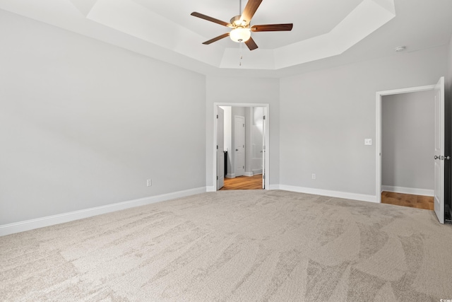 unfurnished bedroom featuring baseboards, a raised ceiling, carpet, and a ceiling fan