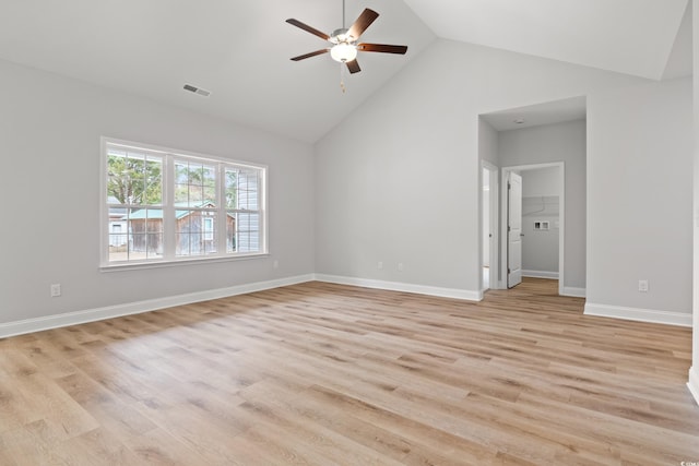 empty room featuring light wood-type flooring, visible vents, baseboards, and high vaulted ceiling