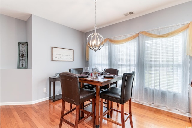 dining area with light wood-type flooring and a notable chandelier