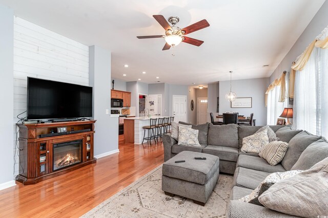 living room featuring ceiling fan, light hardwood / wood-style flooring, and sink