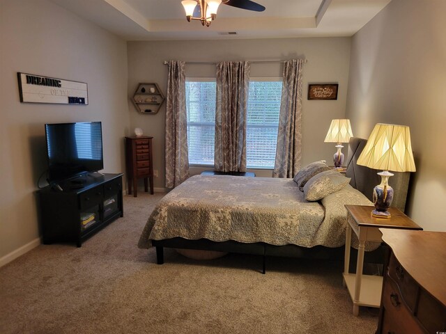 bedroom with light wood-type flooring, a tray ceiling, and ceiling fan