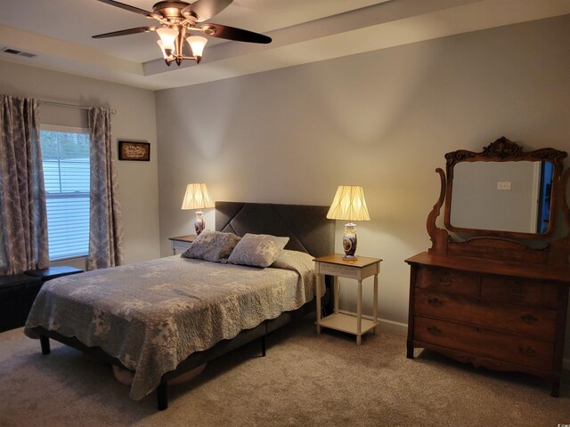 bedroom with hardwood / wood-style floors, ceiling fan, and a tray ceiling