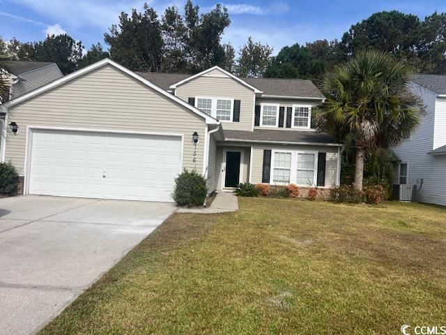 view of front of home with a garage, cooling unit, and a front lawn