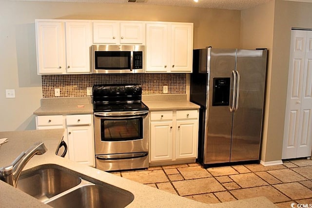 kitchen featuring appliances with stainless steel finishes, tasteful backsplash, white cabinetry, and sink