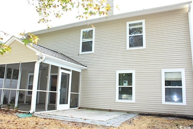 back of property with a sunroom and a patio area