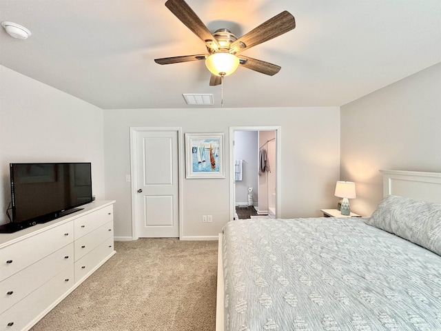 bedroom with ceiling fan, light colored carpet, a walk in closet, and a closet