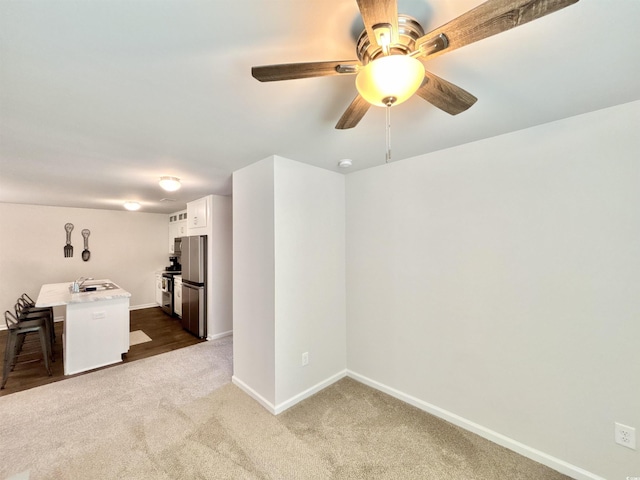 unfurnished room with carpet flooring, ceiling fan, and sink