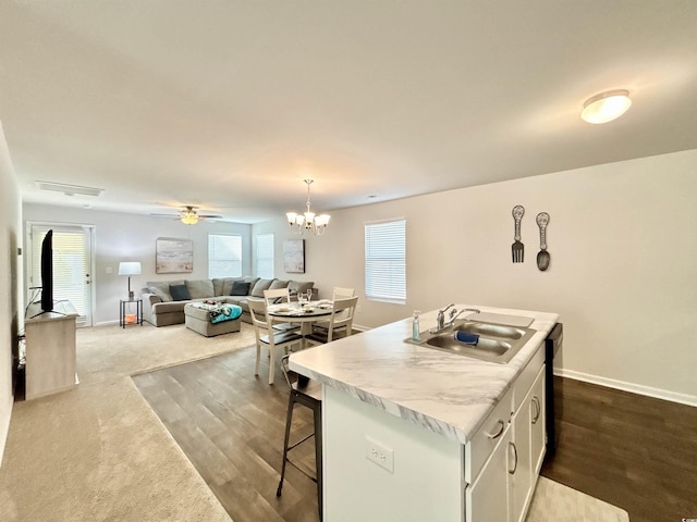 kitchen with dishwasher, white cabinets, sink, an island with sink, and decorative light fixtures