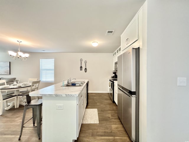 kitchen featuring a kitchen island with sink, hanging light fixtures, white cabinets, and stainless steel appliances