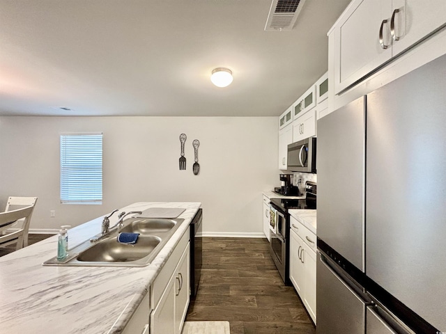 kitchen with light stone countertops, sink, stainless steel appliances, dark hardwood / wood-style floors, and white cabinets